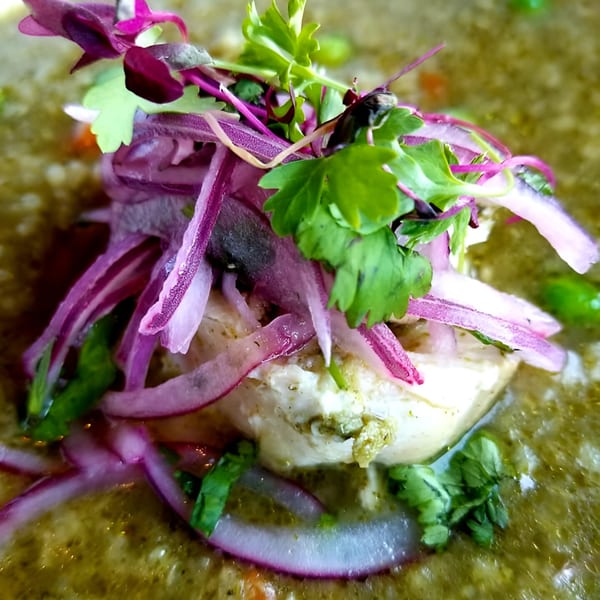 Peruvian ceviche with white fish, red onions, and cilantro in a green sauce.